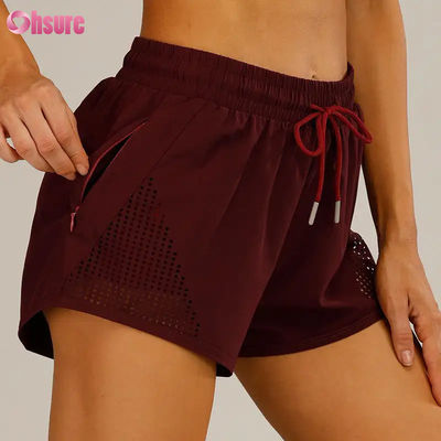 Shorts de sport d'entraînement pour femmes en gros, respirants, avec découpe laser, shorts de jogging avec poche latérale zippée d'échauffement, motif uni